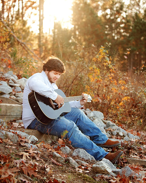 senior portrait photographer near Newnan, teen outside playing a guitar