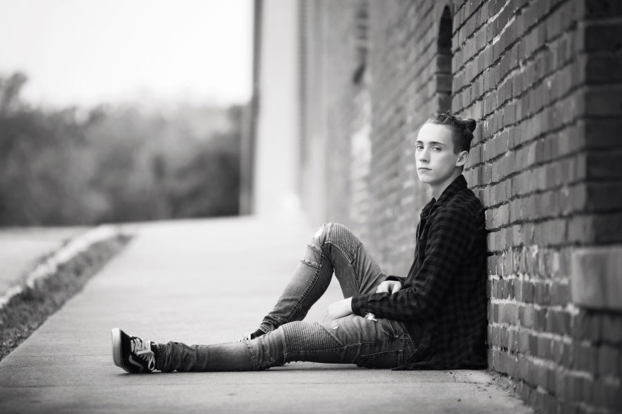 senior portraits near Carrollton, GA; teen sitting by wall downtown