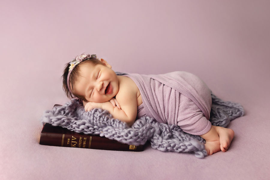 Tallapoosa newborn photographer, baby girl smiling on her parents' Bible
