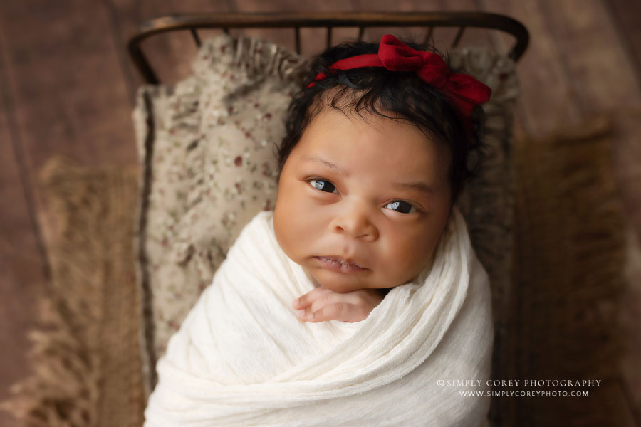 newborn photographer near Carrollton, GA; awake baby girl on bed set