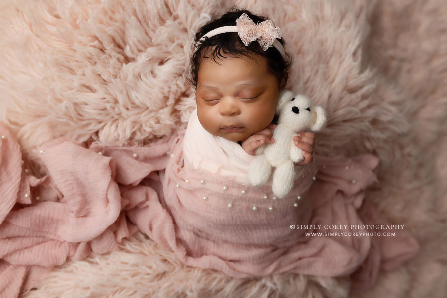 newborn photographer near Villa Rica, baby girl on pink flokati with teddy bear